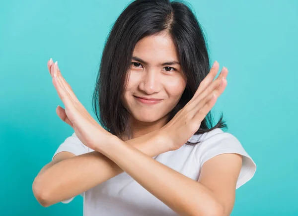 ポートレート幸せなアジアの美しい若い女性の不幸や自信立って身に着けている白いTシャツ 彼女は二つの交差腕を保持言ういいえXサイン スタジオはテキストのためのコピースペースと青の背景で撮影 — ストック写真