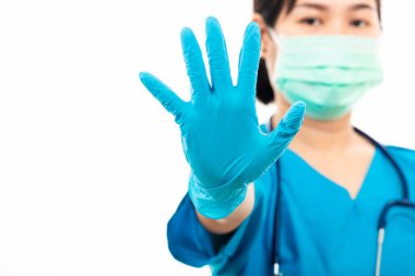 Steteskoplu kadın hemşire lastik eldiven takıyor ve tıbbi maske takıyor, mavi üniformalı kadın doktor dur işareti gösteriyor, stüdyo çekimi beyaz arka planda, tıbbi sağlık konseptinde izole edilmiş.
