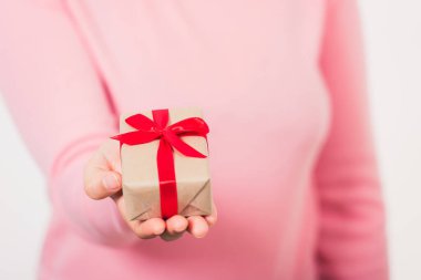 Sevgililer Günü. Beyaz arka planda izole edilmiş kurdeleli küçük hediye paketi hediye paketi sunan kadın elleri, Noel, yeni yıl, doğum günü arka planı konsepti