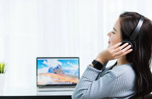 自宅から仕事 アジアの若いビジネスの女性は フロントノートパソコン上のヘッドフォンで音楽に耳を傾けリラックスして感じる疾患コロナウイルスや自宅のオフィスでCovid — ストック写真
