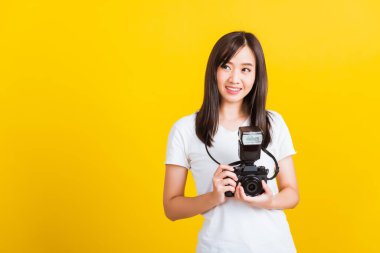 Elinde klasik dijital aynasız fotoğraf makinesi olan mutlu Asyalı genç kadın fotoğrafçının portresi, sarı arka planda izole edilmiş stüdyo çekimi, gençlerin yaşam tarzı seyahat konsepti.