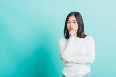 Genç ve güzel Asyalı bir kadının eli yüzünün yanında ve düşünüyor, portre kadın dokunun çene dokunun rüya gibi hayaller kurun şüpheleri var, stüdyo çekimleri mavi arka planda izole edilmiş.