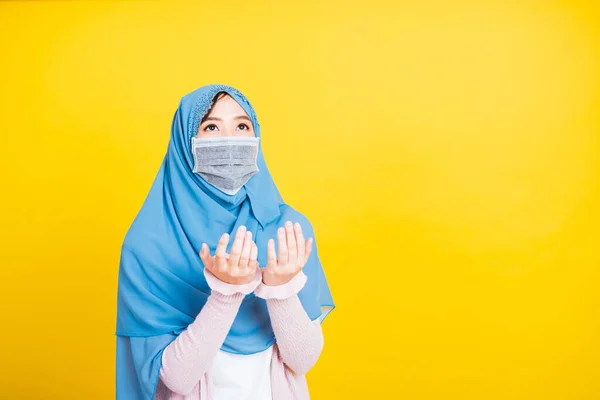 アジア系ムスリムアラブ人 肖像画美しい若い女性宗教的な摩耗ベールヒジャーブと顔のマスクは 彼女は神に祈って手を飾るコロナウイルスを防ぐために保護します 黄色の背景に隔離された — ストック写真