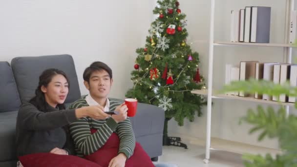 快乐的亚洲年轻夫妇夫妻在客厅里共度寒冬 一起看电视 看电影或娱乐 — 图库视频影像