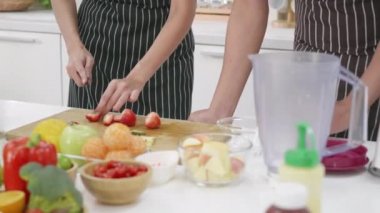 Mutlu Asyalı güzel aile çifti karı koca evde mutfakta taze meyve püresi yapıyor. Kadın ve erkek taze elma meyveleri ve sebzeleri dilimliyor. Sağlıklı yaşam tarzı kavramı