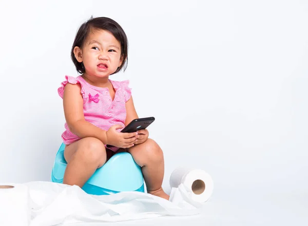 アジアの小さなかわいい赤ちゃんの女の子の教育訓練青のチャンバーポットやポテトに座って トイレペーパーロールでスマートフォンを再生するには スタジオのショットは 白い背景に隔離され トイレWc — ストック写真