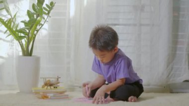Mutlu Asyalı klid çocuk anaokulu, evdeki halının üzerindeki manyetik çizim tahtasında yazıyor. Manyetik çizim tahtası oynayan komik çocuk. Eğitim konsept çizmeyi öğreniyor. Ön görünüm