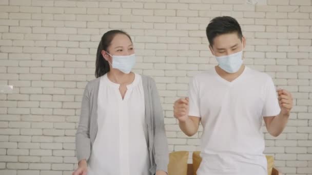幸せなアジアの美しい家族カップルの夫と妻は コロナウイルス Covid のパンデミック隔離中に自宅で一緒に面白い踊り医療面マスクで笑っています スローモーション — ストック動画