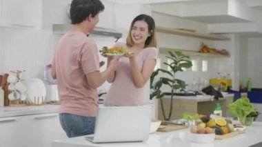 Mutlu Asyalı güzel aile çifti karı koca mutfakta sebze salatası pişiriyorlar. Teşekkür için kadını öpen adam. sağlıklı gıda konsepti