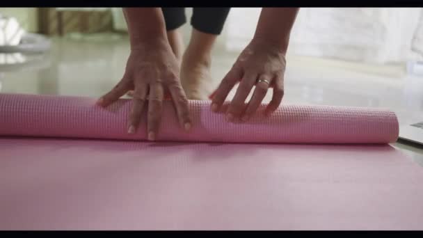 在客厅里做运动前或运动后翻滚粉色瑜伽垫的女人在客厅里做运动前或运动后做运动 在围产期通过运动瑜伽适合做运动女性的锻炼 运动健康的生活方式概念 — 图库视频影像