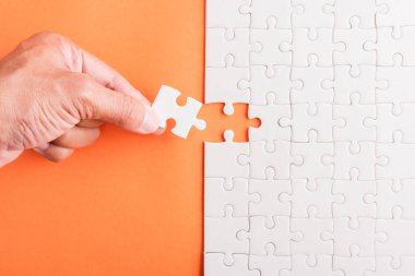 Top view düz konum son parça beyaz kağıt yapboz oyunu çözülmesi için yerleştirilen son parçalar tam görev, turuncu arka plan üzerine stüdyo çekimi, sınav hesaplama konsepti