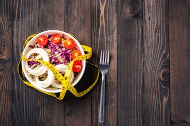 Sağlıklı renkli salata kasesinin üst görüntüsü domatesli taze sebzeli sebze ve siyah ahşap arka planda şerit, sağlıklı salata atıştırmalığı diyet kilo kaybı konsepti.