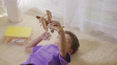 Mutlu Asyalı çocuk uçak pilotu çocuğun arzusu evde halıda yükseklere uçmak. Komik çocuk oyuncak yolcu uçağıyla oynuyor ve pilot olmayı hayal ediyor. Üst görünüm