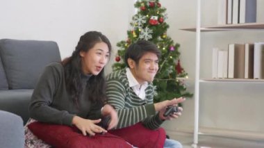 Mutlu Asyalı, genç, güzel aile çifti karı koca gülüyor ve birlikte eğleniyorlar video oyunu oynuyorlar, ellerinde joystick konsolları var. Mutluluk ve oyun konsepti. yavaş çekim