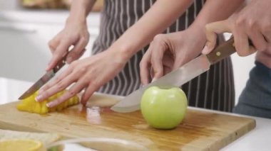 Mutlu Asyalı güzel aile çifti karı koca evde mutfakta taze meyve püresi yapıyor. Kadın ve erkek taze elma meyveleri ve ananas dilimliyor. Sağlıklı yaşam tarzı kavramı