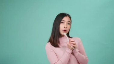 Asyalı genç ve güzel bir kadın, mikrofon dansı yerine diş fırçası gülüyor. Müzikten keyif alıyor, dişçi dişleri şarkı söylüyor. Mavi arka planda, yaşam tarzında diş hijyeninde ve sağlıkta izole edilmiş şekilde eğleniyor..