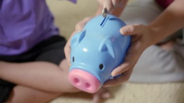 Mutlu Asyalı çocuk anaokulu ve annesi domuzcuğa rozet parası koyuyor. Küçük çocuk evde biriktirdiği bozuk paralarla kumbaraya para koyuyor. Yatırım eğitimi konsepti.