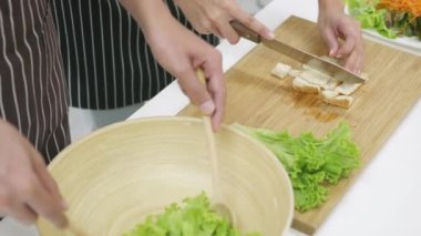 Mutlu Asyalı güzel aile çifti karı koca mutfakta sebze salatası pişiriyorlar. Adam sebzeleri bir fincan dilimlenmiş ekmeğe karıştırdı. Sağlıklı gıda konsepti, yavaş çekim