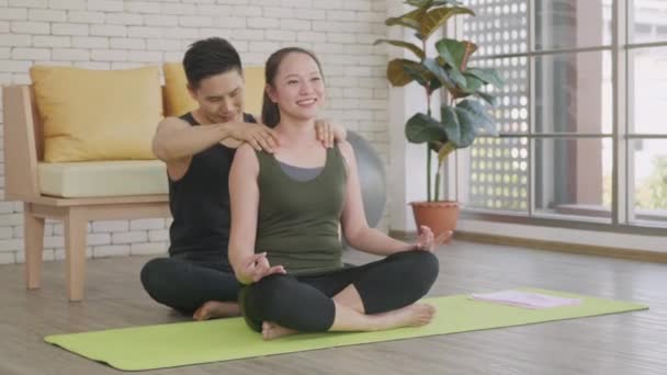 Šťastný asijský krásný životní styl rodinného páru, žena dělá YOGA sedící meditující na lotosu představují cvičení doma a muž masáž ramena pro relaxaci. sport zdravý koncept