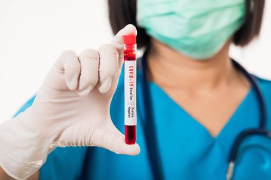 Mavi üniformalı hemşire laboratuarda beyaz arka planda izole edilmiş Coronavirus test kanını, COVID-19 ilaç salgın konseptini incelemek için bir maske takıyor.