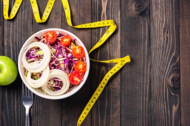 Sağlıklı renkli salata kasesinin üst görüntüsü domatesli taze sebzeli sebze ve siyah ahşap arka planda şerit, sağlıklı salata atıştırmalığı diyet kilo kaybı konsepti.
