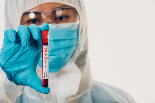 一名身穿Ppe制服的医学科学家在医院的实验室里戴着口罩 拿着试管验血 分析从白色药品Covid 19大流行中分离出来的血液样本 — 图库照片