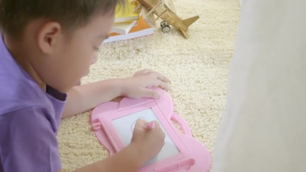 快乐的亚洲Klid小男孩在家里的磁板上写在地毯上 有趣的孩子玩磁力画板 教育学习绘画概念 背景色 — 图库视频影像