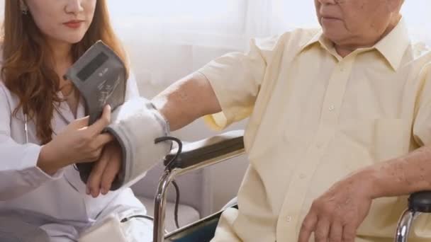 Young Nurse Measuring Blood Pressure Checkup Pensive Disabled Elderly Patient — Stock Video