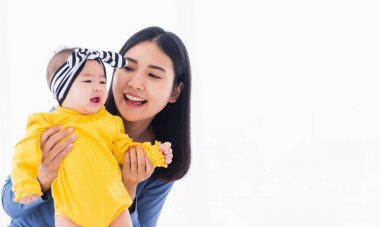 Güzel Asyalı bir annenin portresi, yeni doğmuş bebeğiyle evde oynayıp gülümsüyor ebeveyn anne ve küçük çocuk yatak odasında dinleniyor, aile birlikte eğleniyor.