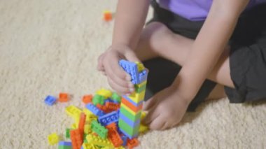 Mutlu Asyalı çocuk anaokulu evde kalıp yaratıcı plastik oyuncak blokları oynuyor. Renkli bloktan bir kule inşa eden komik küçük çocuk, eğitici inşaat oyunu konsepti