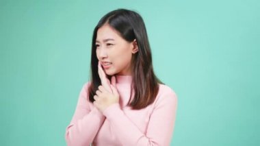 Genç Asyalı güzel bir kadının portresi diş tellerine silikon diş teli takıyor ve mavi arka planda el izole edilmiş bir şekilde yanağını tutarak diş ağrısı çekiyor. Dişleri ağrıyan bir kadın diş ağrısı