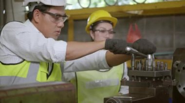 Asya profesyonel makine mühendisi ve operasyon ekibi üniforma güvenliği giyiyorlar. Metal üretimi fabrikasında çalışıyorlar. Ağır endüstri torna işçisi erkek ve kadın.