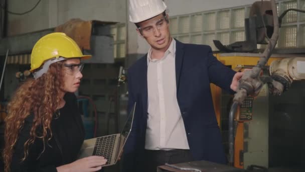 白种人维修工程师男性和不同的工厂女工在工厂 主管和工业生产 慢动作等方面讲 介绍或解释机器人焊机 — 图库视频影像