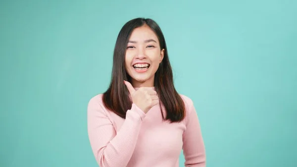 肖像画若いアジアの幸せな美しい女性の笑顔は青の背景に隔離された親指の指を示す歯にシリコーン歯列矯正家臣を着用してください 歯科衛生と健康の概念 — ストック写真