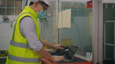Asyalı fabrika işçisi iş görüşmesi olarak telefon ahizesi sunuyor, kontrol odasında teknisyen kaskı takıyor telefonda konuşuyor, yavaş çekim.