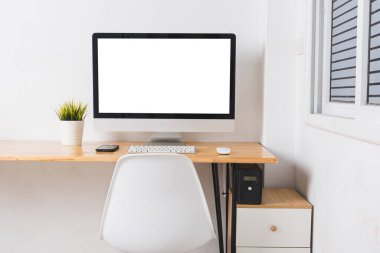 İş masasında beyaz boş ekranlı bilgisayar monitörü kablosuz fare, beyaz duvar arkaplanı üzerinde klavye, çağdaş ekipman çalışma alanı fotoğrafı