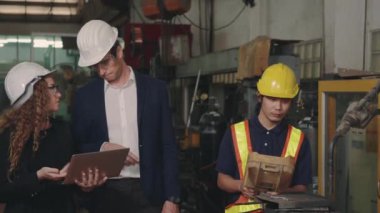 Üç ağır endüstri mühendisliği bilgisayar başında bilgi tartışırken kapalı alanda otomatik programlama için kaynak endüstrisi üretiyor.