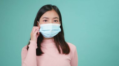 Genç Asyalı mutlu kadın portresi koruyucu yüz maskeni çıkar ve gülümse. Dişlerinde silikon diş telleri göster. Kadın steril tıbbi maskeyi çıkardı, Coronavirus 'a karşı zaferi kutladı.