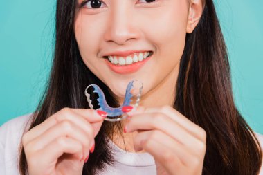 Teeth retaining tools after removable braces, Portrait young Asian beautiful woman smiling holding silicone orthodontic retainers for teeth, Orthodontics dental healthy care concept clipart