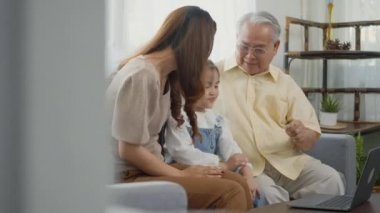 Mutlu aile büyükbabası, kızı ve torunu internette görüntülü konuşma yapıyorlar. Babasıyla dizüstü bilgisayar kullanıyorlar. Yaşlı büyükbaba, küçük torunu ve annesini evinde kucaklıyor.