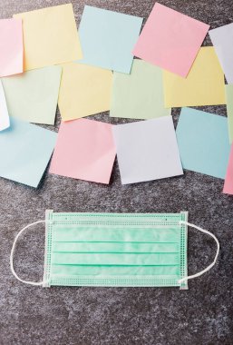 Beton arka planda yüz maskesi koruyucu karantina hastalığı koronavirüsü ya da COVID-19 ile birçok boş kağıt yapıştırma listesinin üzerinde ve bugün not çubuğu belleği çalışması yaz