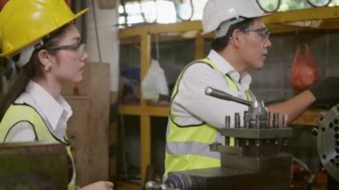 Asya profesyonel makine mühendisi ve operasyon ekibi üniforma güvenliği giyiyorlar. Metal üretimi fabrikasında çalışıyorlar. Ağır endüstri torna işçisi erkek ve kadın.