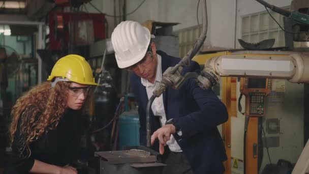 白种人维修工程师男人和各种不同的女工厂工人 戴着硬帽 在工厂 主管和工业生产中谈论 介绍或解释机器人焊机 — 图库视频影像