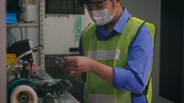 Asyalı fabrika işçisi teknisyen atölyede dijital vernier kalibreli çelik büyüklüğündeki detayı ölçüyor.