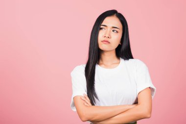 Asyalı mutlu bir portre kollarını kavuşturmuş güzel bir genç kadın kızgın ve kızgın yumruğunu kaldırıyor öfkeyle bağırırken pembe arka planda stüdyo çekimi.