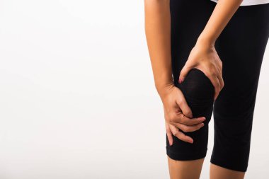Yakındaki genç kadın diz ağrısı çekiyor ve el eklem ağrısı, diz ağrısı, beyaz arka planda izole edilmiş stüdyo çekimi, romatizma sağlık ve tıbbi fizyoterapi konsepti kullanıyor.