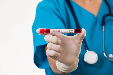 Mavi üniformalı hemşire laboratuarda beyaz arka planda izole edilmiş Coronavirus test kanını, COVID-19 ilaç salgın konseptini incelemek için bir maske takıyor.