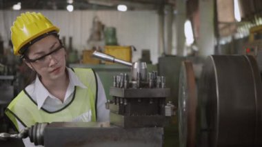 Asyalı profesyonel makine mühendisi ya da operatör kadın üniforma gözlüğü takıyor atölye metal torna fabrikasında çalışıyor ağır sanayi torna işçisi kadın, yavaş çekim işçisi