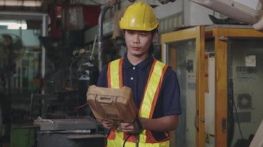Asyalı mühendis otomatik programlama için kaynak makinesini kontrol edip kontrol ediyor. Kapalı alanda kaynak yapıyor, endüstriyel, yavaş çekimde.