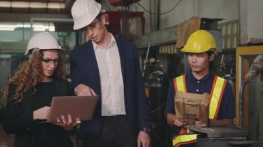 Üç ağır endüstri mühendisliği bilgisayar başında bilgi tartışırken kapalı alanda otomatik programlama için kaynak endüstrisi üretiyor.